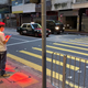 A pedestrian bathed in red light waits for a walk signal at a crosswalk.